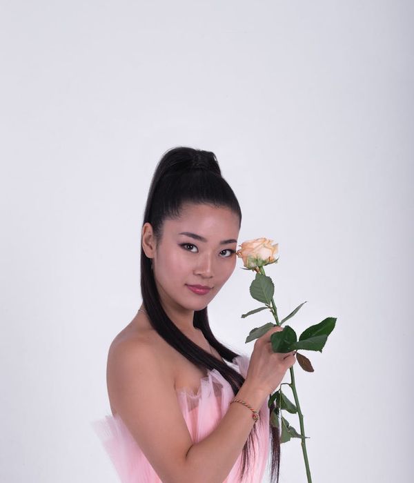 Woman in a graceful yoga pose with soft pink lighting